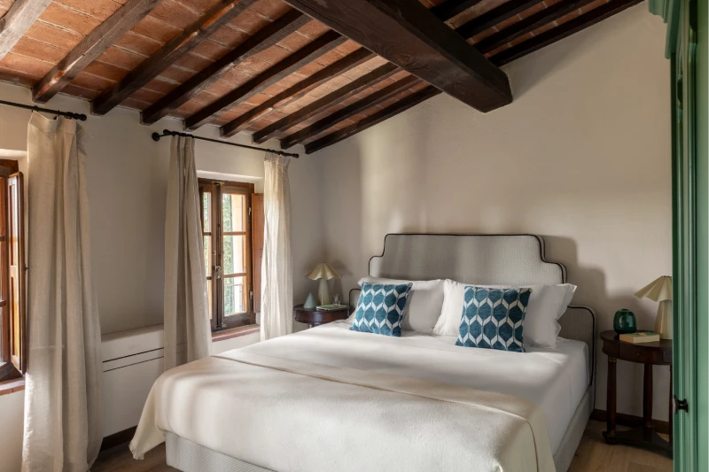 Bright double bedroom with wooden beams, white bed and blue cushions, Tuscan charm in the Crete Senesi countryside - Villa San Barolomeo, BZAR hotels in Tuscany