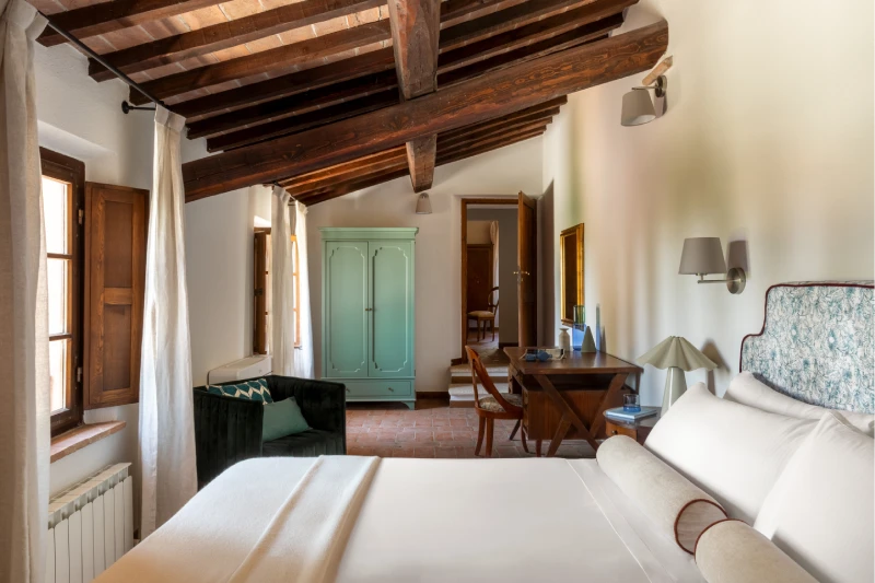 Spacious bedroom with white bed, aqua green wardrobe, small sofa and wooden windows, Tuscan style near Asciano - Villa San Barolomeo, BZAR hotels in Tuscany