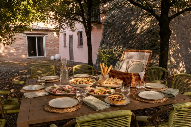 Shaded garden lounge with white wrought-iron seating and table, ideal for relaxing stays in the Crete Senesi countryside - Villa San Barolomeo, BZAR hotels in Tuscany
